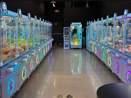Corredor iluminado com máquinas de pelúcias em um salão de arcade